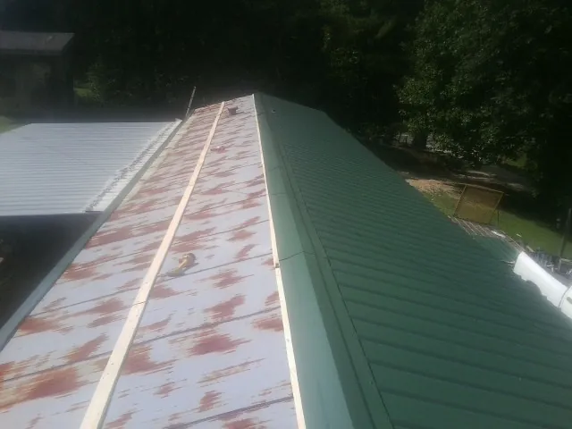 Old rusted panels beside newly installed green metal roofing — Wind Damage Roof Repair by Roofing Brothers in Long Lake