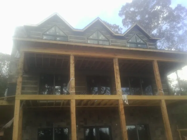 Dormers and porch framing on a large log home under construction — Roof Coating work by our crew in Long Lake