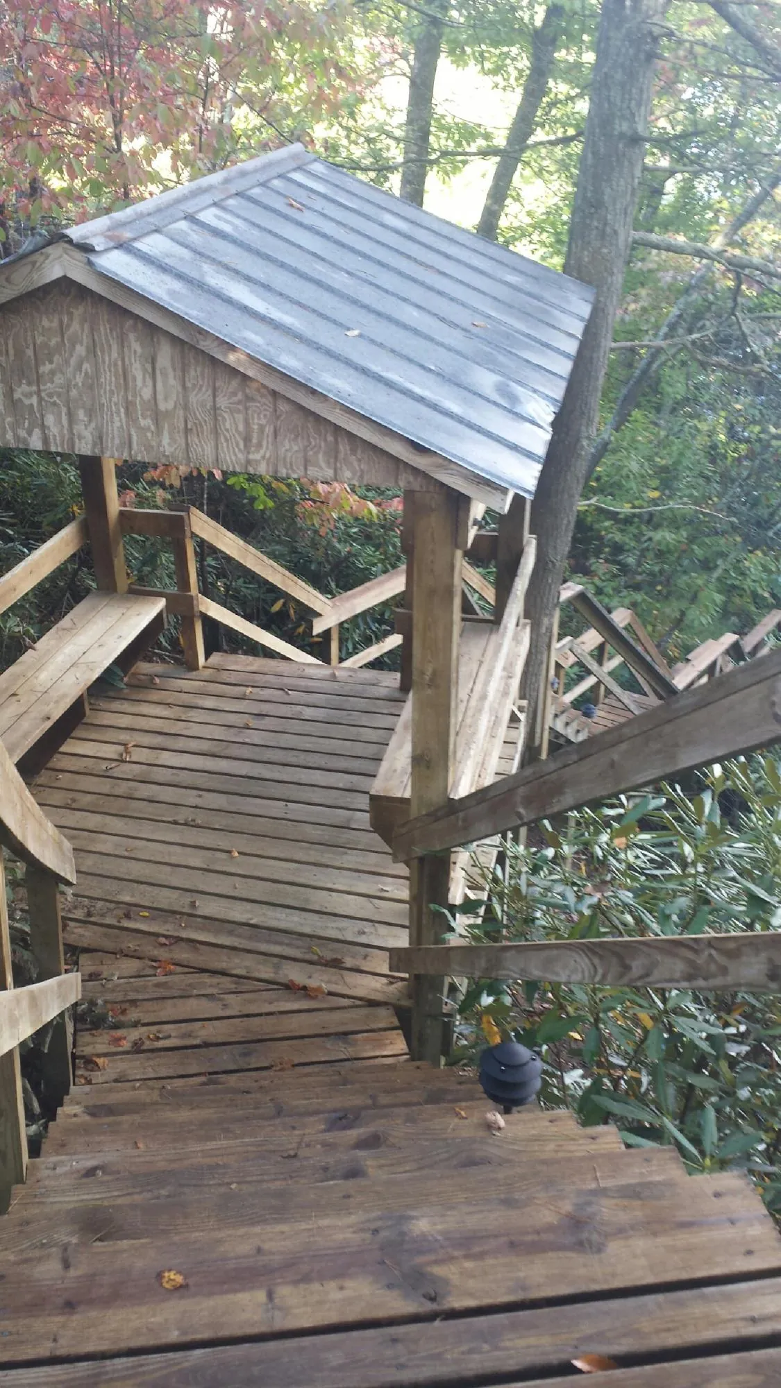 Metal roofed shelter over wooden steps on a wooded walkway — Skylight Repair & Installation work by our crew in Long Lake