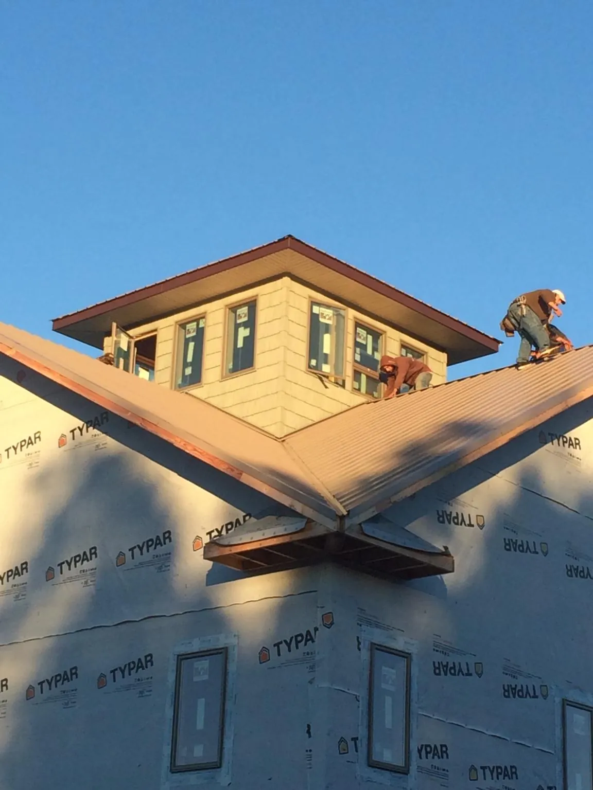 Roofers working around a rooftop cupola on a new metal roof at sunset — Roof Waterproofing in Long Lake by Roofing Brothers